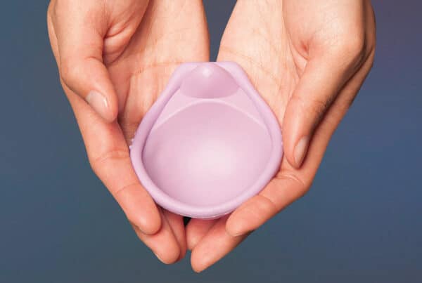 A woman's hands cupped together and holding the Caya contraceptive diaphragm.