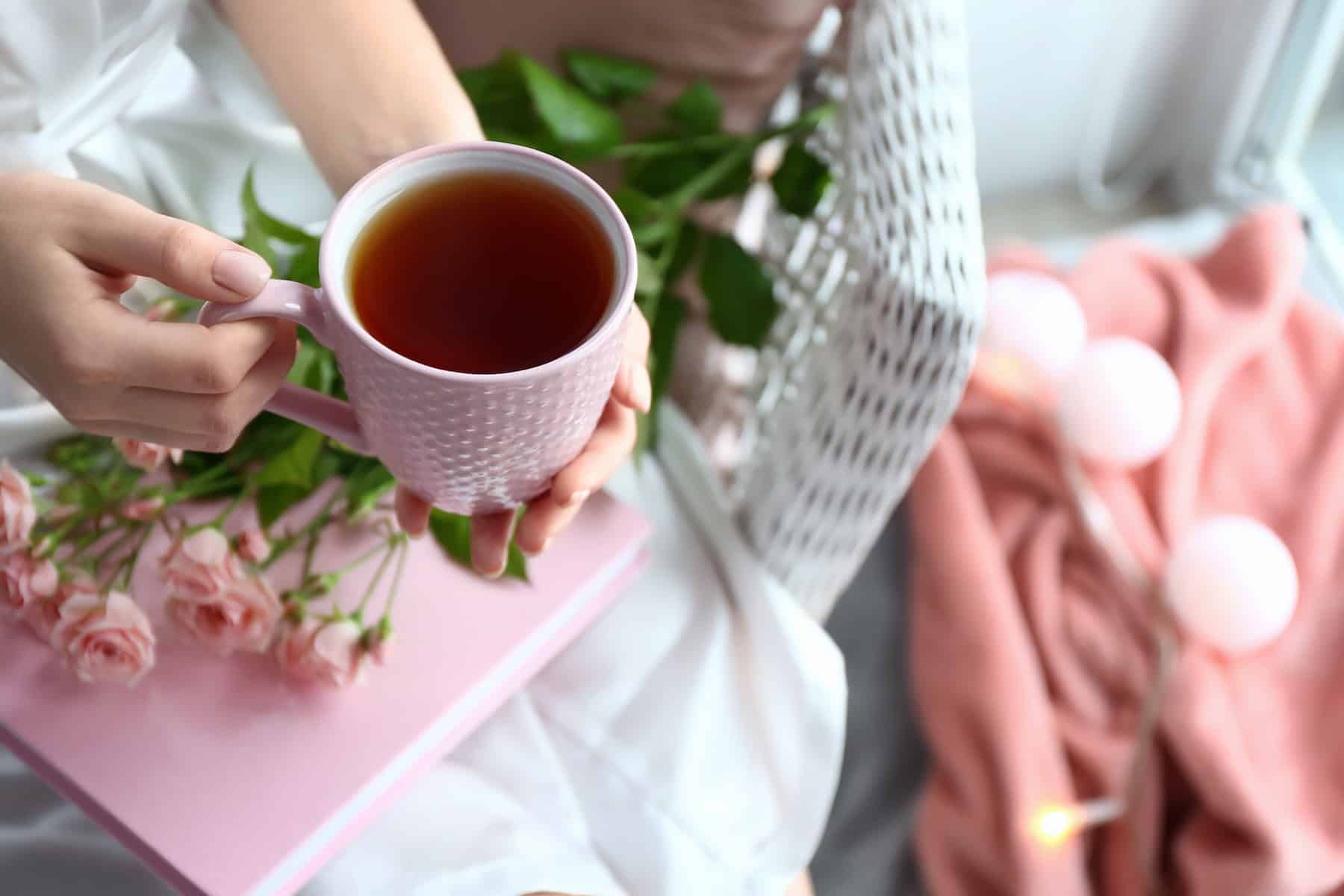 Woman drinking hot tea at home, closeup