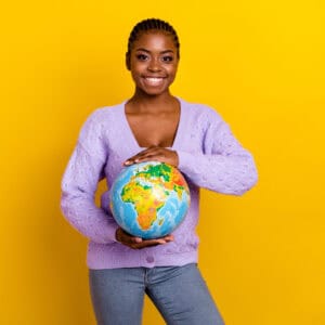 Photo of charming cheerful person arms hold planet earth globe toothy smile isolated on yellow color background.