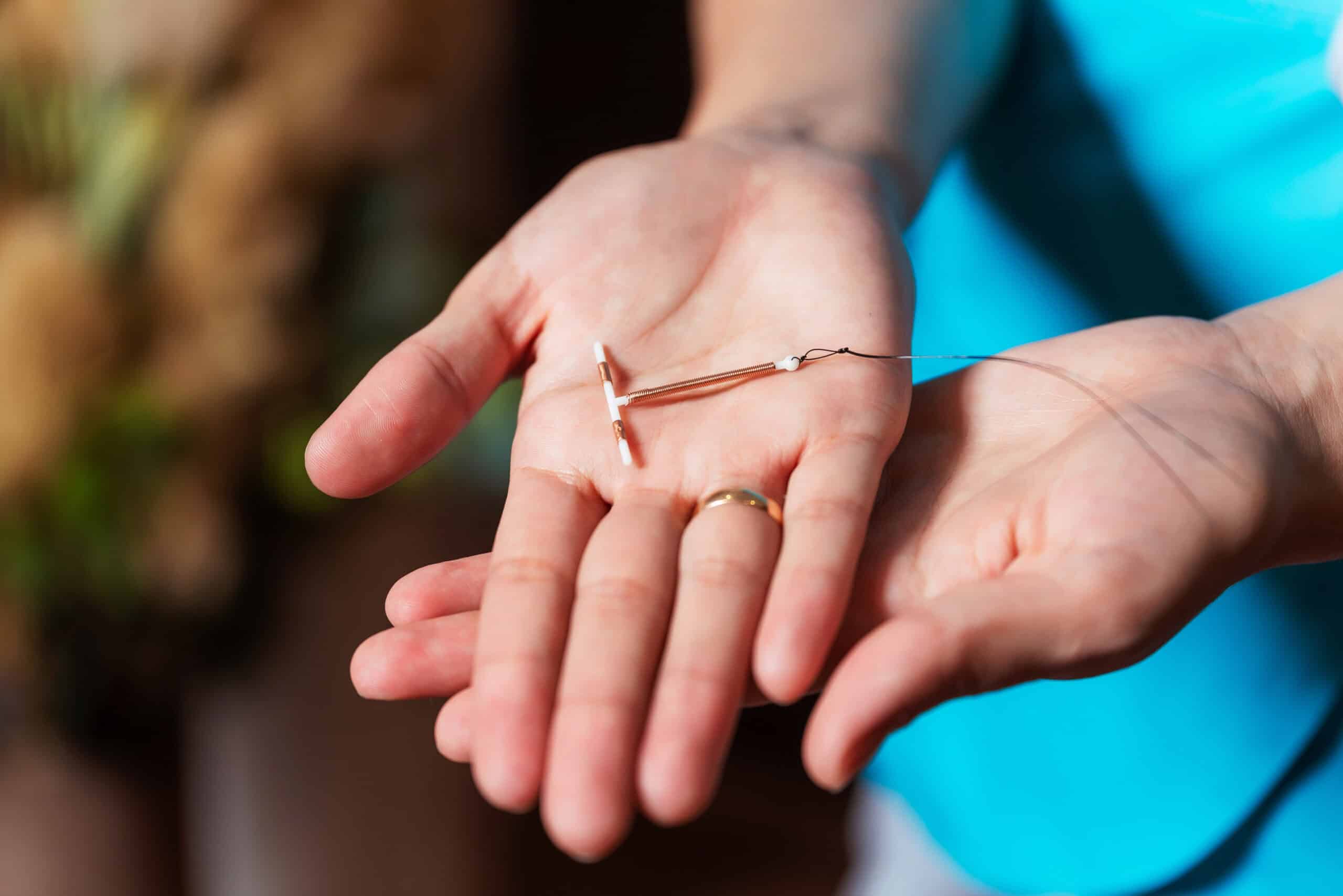 Female contraception copper IUD in the hands of a provider wearing a blue shirt